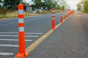 A low-angle view of many reflective orange plastic poles set up as a sign to prevent oncoming traffic. photo