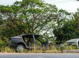 Side view of a black car wreck dismantled to its steel frame. photo