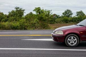 un de cerca ver de el lado de un nuevo pista la carretera con un rojo coche paso por. foto