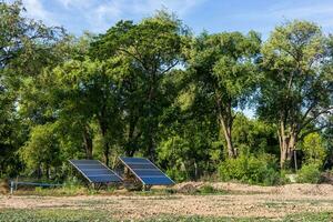 View Two large solar panels are mounted on barren ground. photo