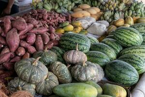 Heaps of melons, pumpkins, sweet potatoes and many others stacked together. photo