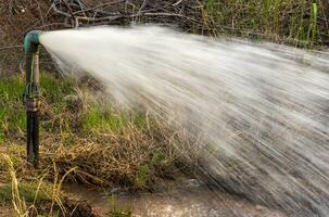 Close-up view of water gushing violently out of a water supply pipe. photo