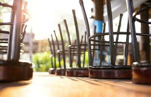 A close-up view of round wooden chairs with iron legs turned upside down on a table. photo