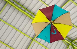 A low-angle view passes through a colorfully decorated umbrella hanging beneath a roof structure. photo