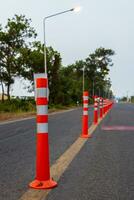 A low-angle view of many reflective orange plastic poles set up as a sign to prevent oncoming traffic. photo