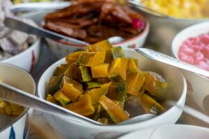 Close-up view of pumpkin slices in syrup and various other colorful sweets. photo
