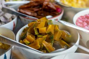 Close-up view of pumpkin slices in syrup and various other colorful sweets. photo