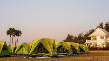 Scenery of many green tents for outdoor activities set up on dry lawn outside. photo