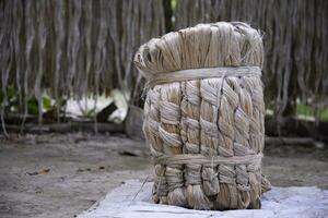 A thick brown  bundle of raw jute has on the ground photo