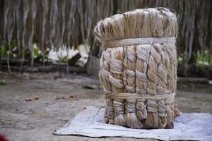 A thick brown  bundle of raw jute has on the ground photo