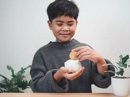 A boy putting coins into piggy bank. Learning financial responsibility and projecting savings. savings concept. investment concept. photo