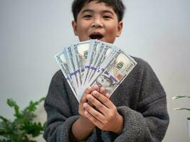 el chico alegremente sostiene el dinero. dinero ahorro concepto, inversión, finanzas. foto