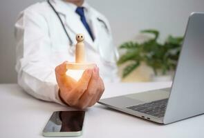 Doctor holding and show wood doll at hospital office. Medical health care and medical services. photo