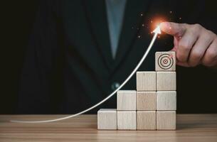 Businessman pin in the selection of target on wooden block which prints a target icon. Business goals and objectives concept. business competition. business strategy photo