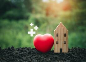 The concept of health insurance and medical welfare. Model wooden house and red heart with plus icon. Health insurance and access to health care. health care planning photo