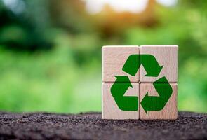 Concepts of waste reduction, pollution, reuse, efficient use of resources. Environmental protection sign by recycling on circular wooden blocks on nature background. photo