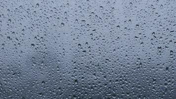 chuva solta em vidro janela com azul fundo dentro monção temporada. video