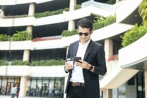 Asian young businessman Searching for information on internet with smartphone. Business, education, lifestyle concept. photo