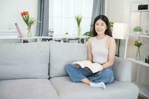 Asian woman happy smile Beautiful Asian woman relaxing reading book in bedroom at home. home relaxation concept photo