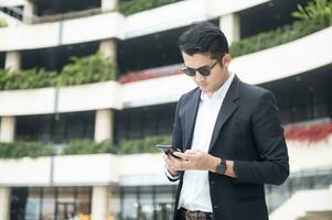 Asian young businessman Searching for information on internet with smartphone. Business, education, lifestyle concept. photo