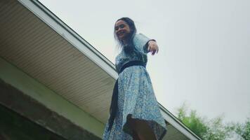 ett asiatisk kvinna gående på de balkong vägg i främre av de hus lyckligt video