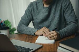 man with learning language during online courses education. e-learning webinar online class by using laptop computer and writing notebook at workplace, development or knowledge improvement concept. photo