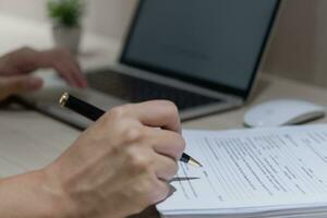 mano utilizando escritura bolígrafo con papeleo en negocio empresa personal información o firma trabajo solicitud documentos en escritorio. foto