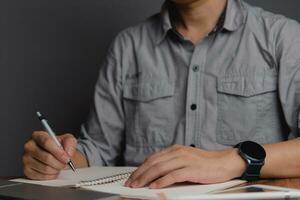 hand holding pen with writing or planning journal on note book in office photo