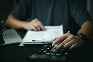 Businessman using calculator and accounting documents at desk with laptop computer. photo