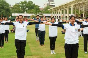 nuevo Delhi, India, junio 21, 2023 - grupo yoga ejercicio sesión para personas a yamuna Deportes complejo en Delhi en internacional yoga día, grande grupo de adultos asistiendo yoga clase en Grillo estadio foto