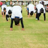 New Delhi, India, June 21, 2023 - Group Yoga exercise session for people at Yamuna Sports Complex in Delhi on International Yoga Day, Big group of adults attending yoga class in cricket stadium photo