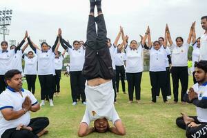 nuevo Delhi, India, junio 21, 2023 - grupo yoga ejercicio sesión para personas a yamuna Deportes complejo en Delhi en internacional yoga día, grande grupo de adultos asistiendo yoga clase en Grillo estadio foto