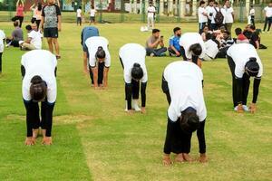 New Delhi, India, June 21, 2023 - Group Yoga exercise session for people at Yamuna Sports Complex in Delhi on International Yoga Day, Big group of adults attending yoga class in cricket stadium photo