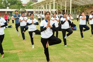 nuevo Delhi, India, junio 21, 2023 - grupo yoga ejercicio sesión para personas a yamuna Deportes complejo en Delhi en internacional yoga día, grande grupo de adultos asistiendo yoga clase en Grillo estadio foto