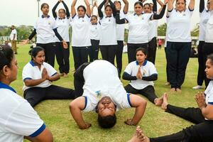 New Delhi, India, June 21, 2023 - Group Yoga exercise session for people at Yamuna Sports Complex in Delhi on International Yoga Day, Big group of adults attending yoga class in cricket stadium photo