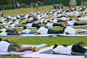 New Delhi, India, June 21, 2023 - Group Yoga exercise session for people at Yamuna Sports Complex in Delhi on International Yoga Day, Big group of adults attending yoga class in cricket stadium photo