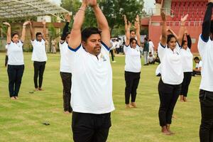 nuevo Delhi, India, junio 21, 2023 - grupo yoga ejercicio sesión para personas a yamuna Deportes complejo en Delhi en internacional yoga día, grande grupo de adultos asistiendo yoga clase en Grillo estadio foto