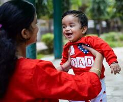 Loving mom carrying of her baby at society park. Bright portrait of happy mum holding child in her hands. Mother hugging her little 9 months old son. photo