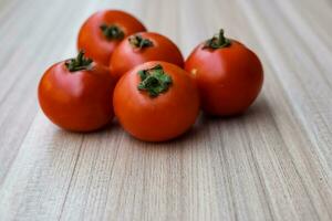 Red tomato on plain wooden table, essential vegetables for all essential foods, view of unpeeled vegetables with plain background photo