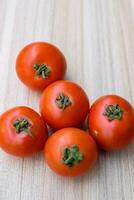 Red tomato on plain wooden table, essential vegetables for all essential foods, view of unpeeled vegetables with plain background photo