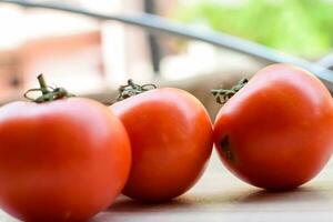 Red tomato on plain wooden table, essential vegetables for all essential foods, view of unpeeled vegetables with plain background photo