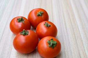 Red tomato on plain wooden table, essential vegetables for all essential foods, view of unpeeled vegetables with plain background photo