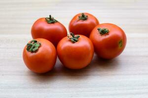 Red tomato on plain wooden table, essential vegetables for all essential foods, view of unpeeled vegetables with plain background photo