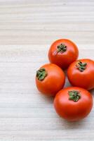 Red tomato on plain wooden table, essential vegetables for all essential foods, view of unpeeled vegetables with plain background photo