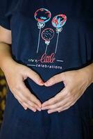 A pregnant Indian lady poses for indoor pregnancy shoot and hands on belly, Indian pregnant woman puts her hand on her stomach with a maternity dress inside her home photo