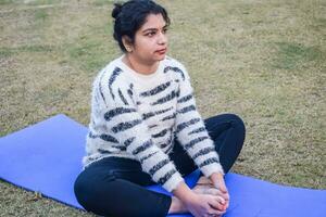 Young Indian woman practicing yoga outdoor in a park. Beautiful girl practice basic yoga pose. Calmness and relax, female happiness. Basic Yoga poses outdoor photo