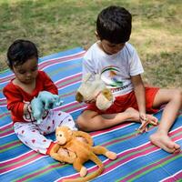 dos contento Niños en sociedad parque, contento asiático hermanos quien son sonriente felizmente juntos. hermanos jugar al aire libre en verano, mejor amigos. niñito bebé chico jugando con su contento hermano en el jardín foto