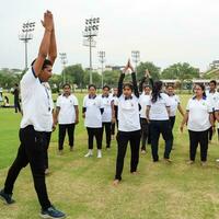 New Delhi, India, June 21, 2023 - Group Yoga exercise session for people at Yamuna Sports Complex in Delhi on International Yoga Day, Big group of adults attending yoga class in cricket stadium photo