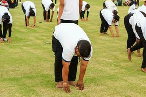 nuevo Delhi, India, junio 21, 2023 - grupo yoga ejercicio sesión para personas a yamuna Deportes complejo en Delhi en internacional yoga día, grande grupo de adultos asistiendo yoga clase en Grillo estadio foto