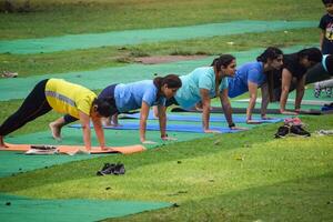 New Delhi, India, June 20 2023 - Group Yoga exercise class Surya Namaskar for people of different age in Lodhi Garden, International Yoga Day, Big group of adults attending a yoga class in park photo